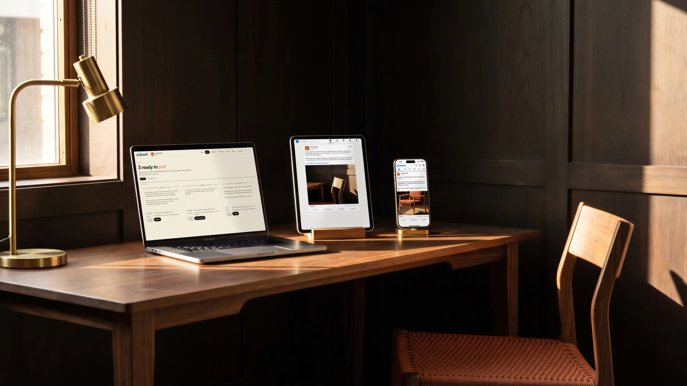 A furniture maker’s showroom news as three posts on a desk: all three on a laptop, LinkedIn on a tablet, Facebook on a phone.