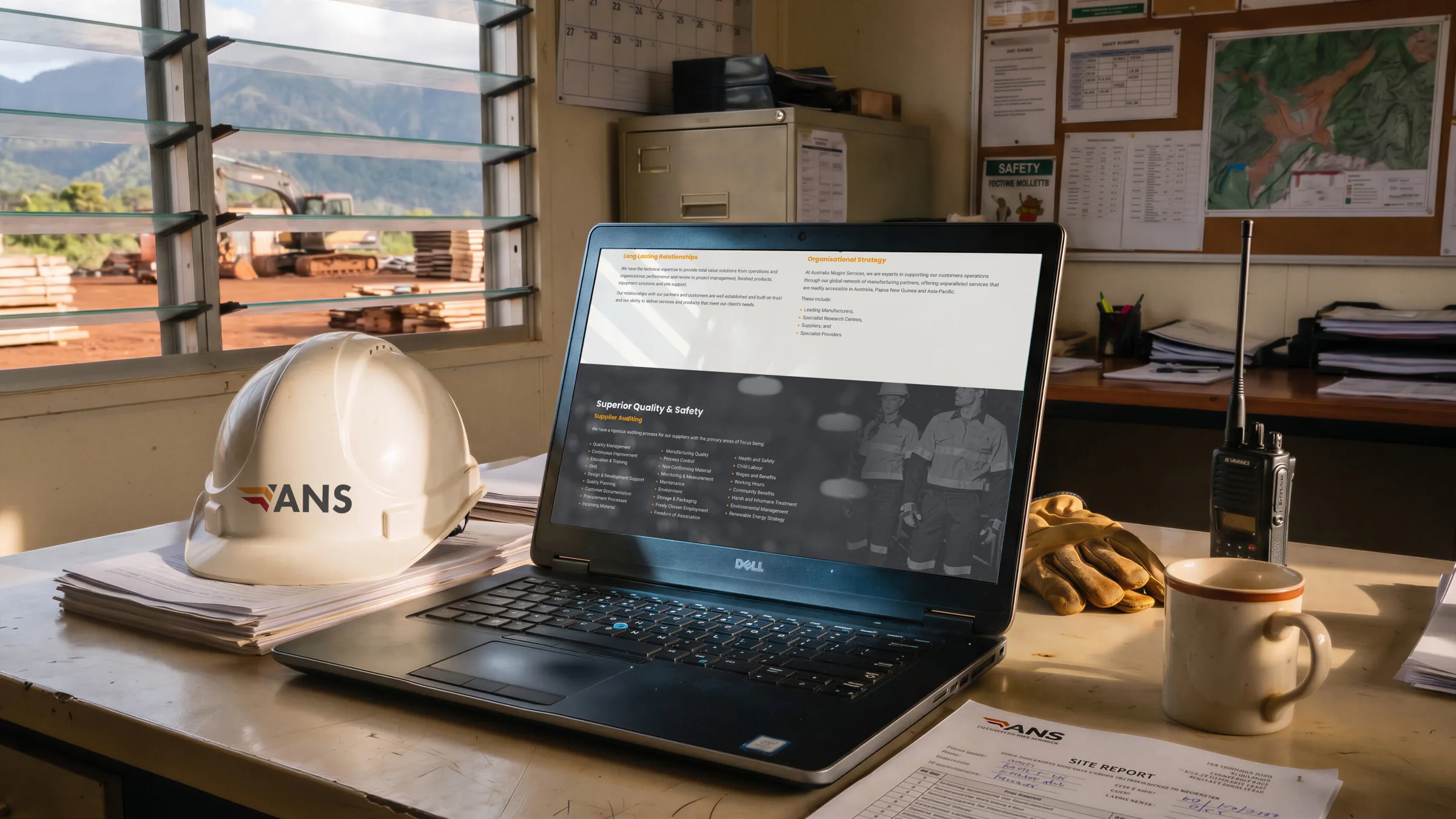The site on a laptop in a mine site office, Total Value Solutions on screen, an ANS hard hat beside it.