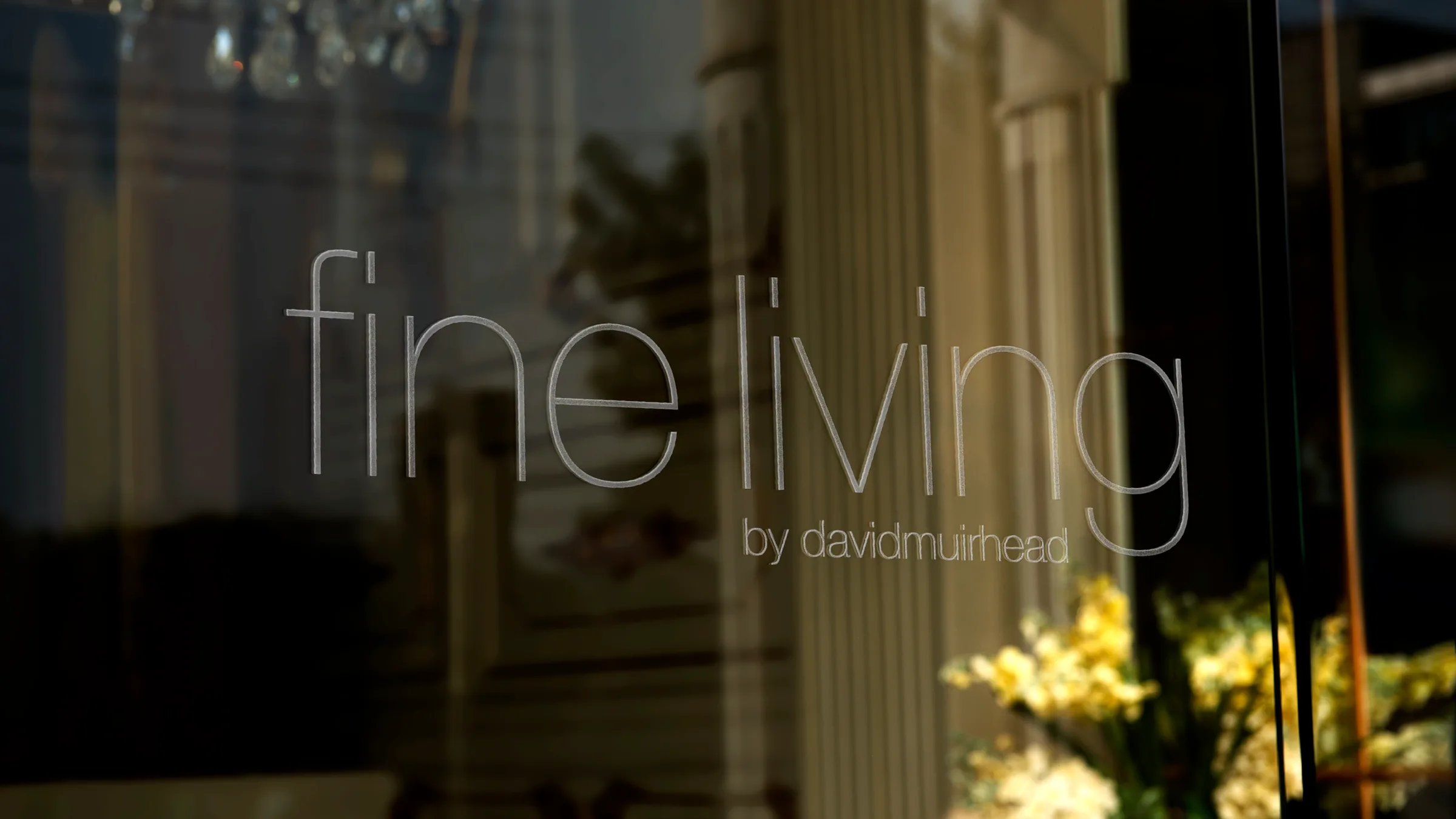 Fine Living by David Muirhead etched across the showroom window at dusk.