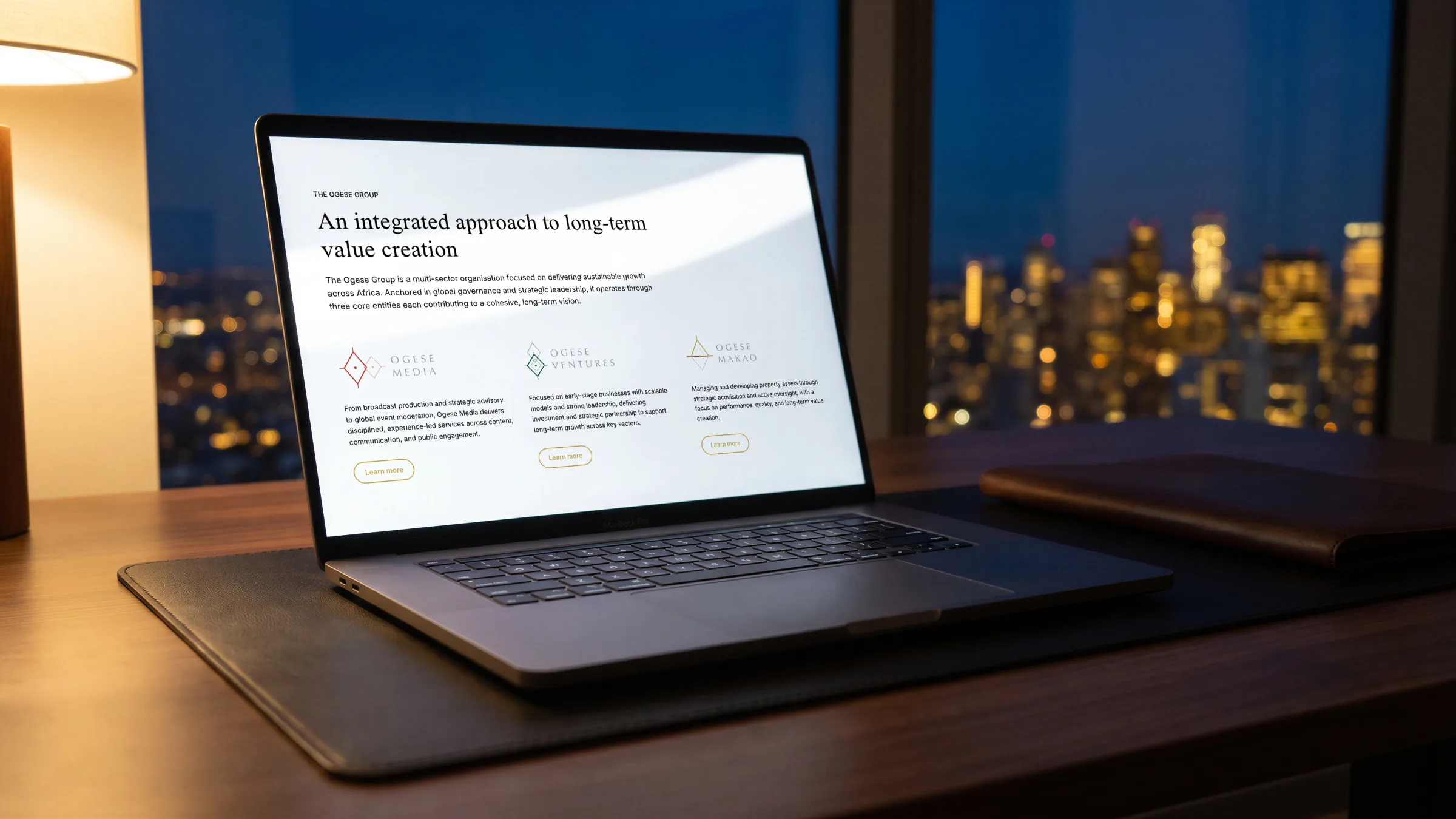 The site open on a laptop at night, a lit city skyline through the window.