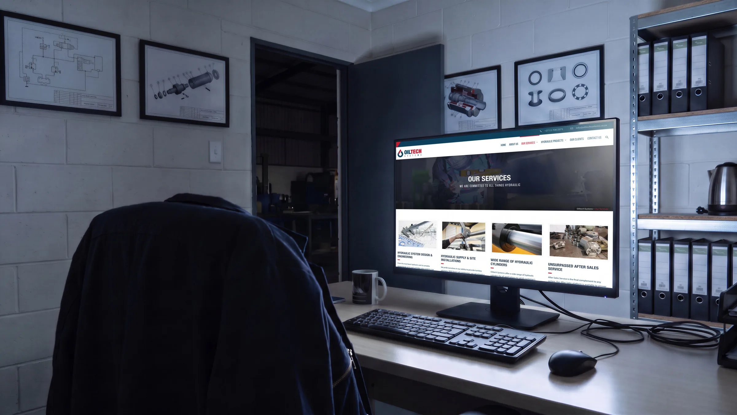 The Hydraulic Projects page on a rugged laptop on the workshop bench, an Oiltech hard hat beside it, a fitter working behind.