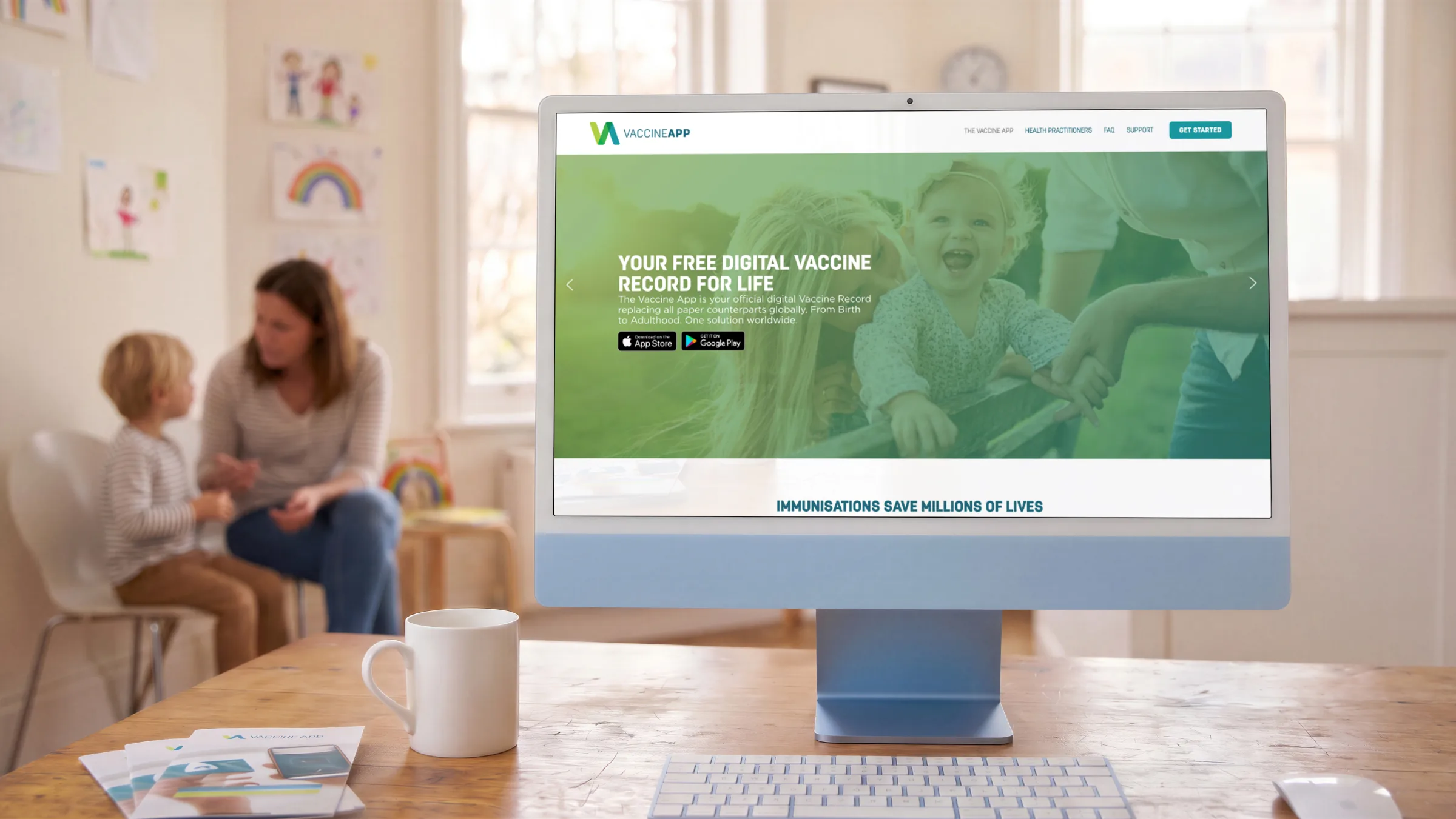 The home page on a desktop in a paediatric waiting room, mother and child beyond.